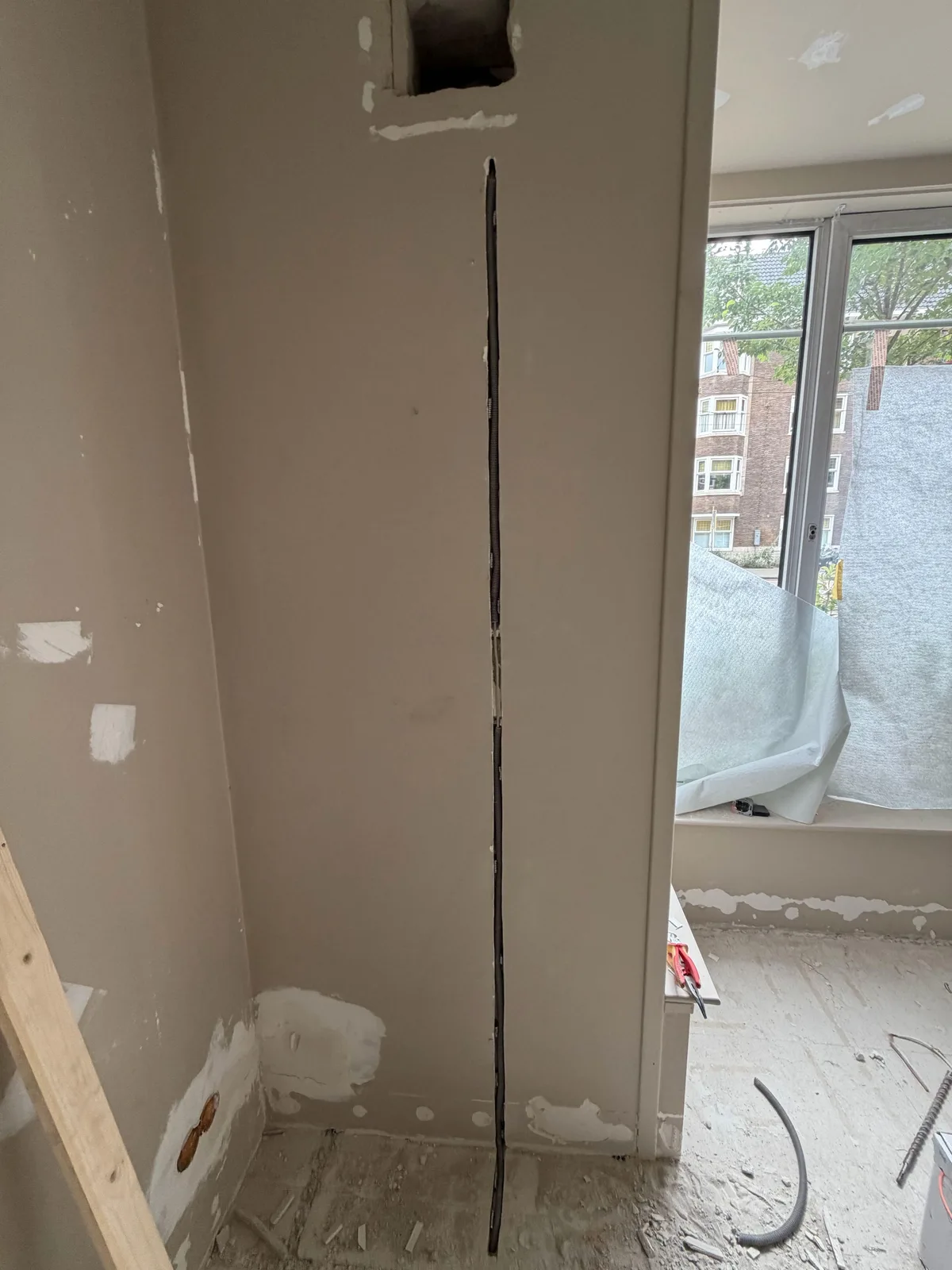 Lange verticale gefreesde sleuf in een muur met een kabel in flexbuis