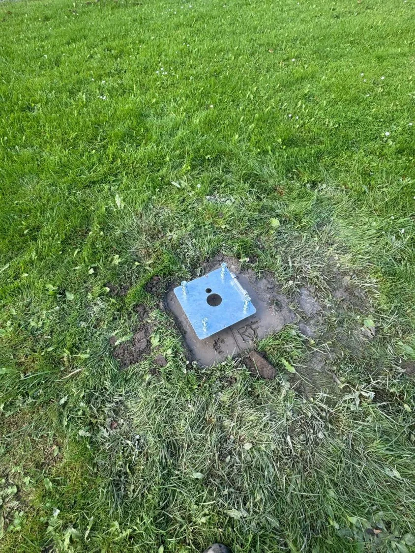 Gegalvaniseerd grondanker met draadeinden, net in beton gestort in het gras