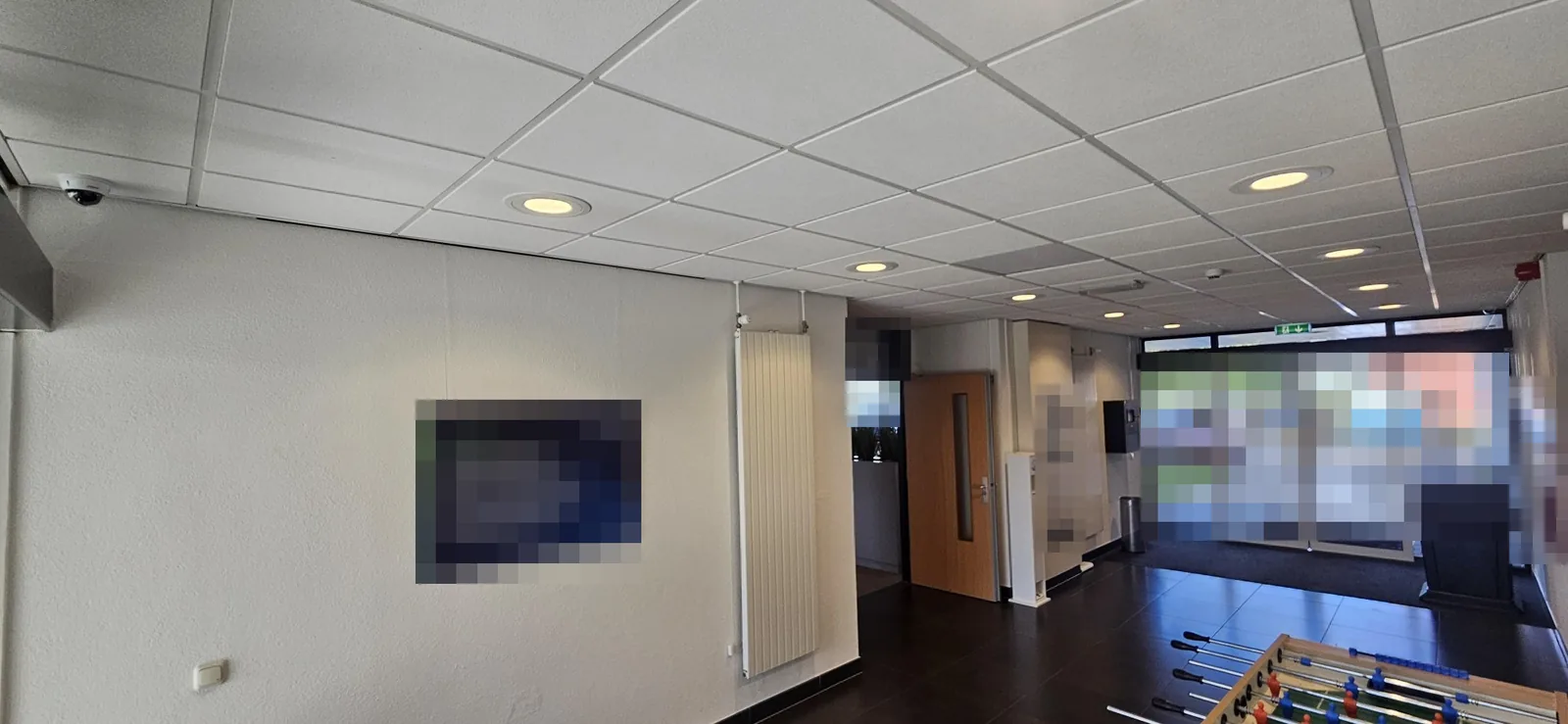 Hal van een kantoorpand in Almere met links aan het plafond een Dahua-domecamera en achterin de glazen buitendeuren