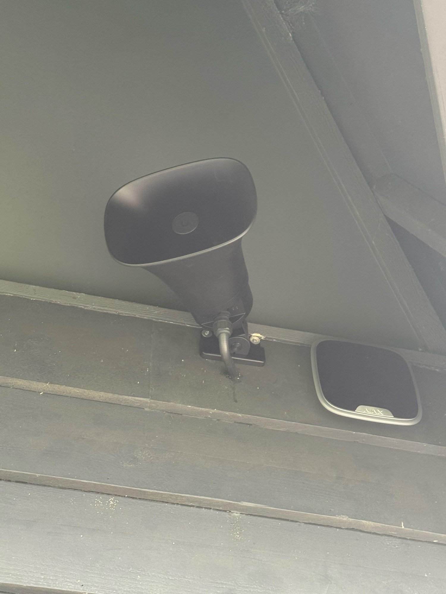 Grijze hoorn en een witte wifi-zender onder het plafond van de overkapping