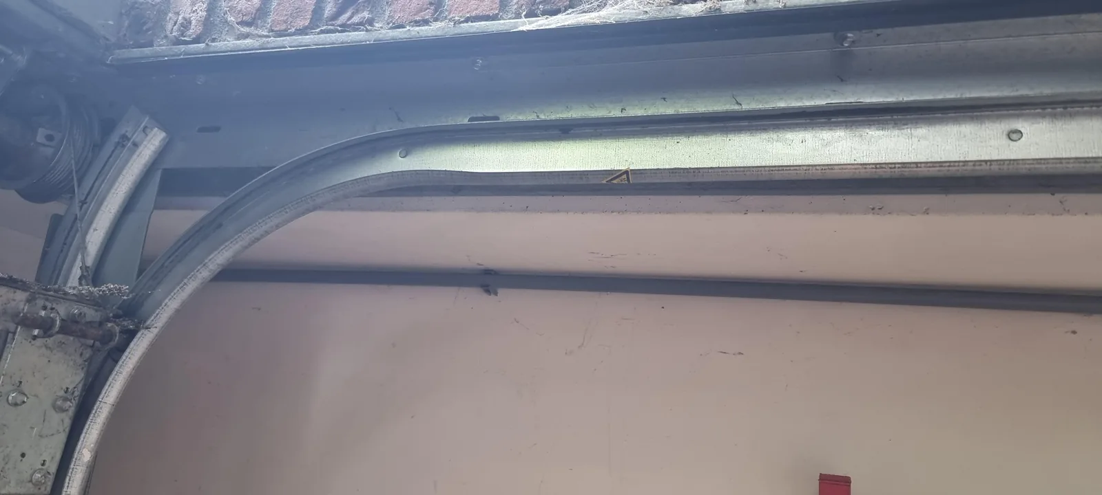 Zwarte installatiebuis met de camerakabel langs de rail van de garagedeur
