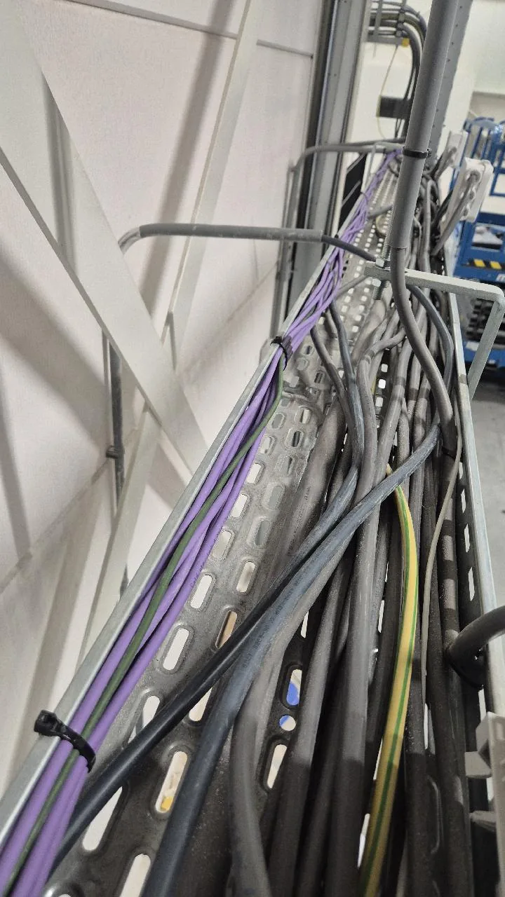 Paarse datakabels met tiewraps gebundeld in een kabelgoot, naast andere kabels