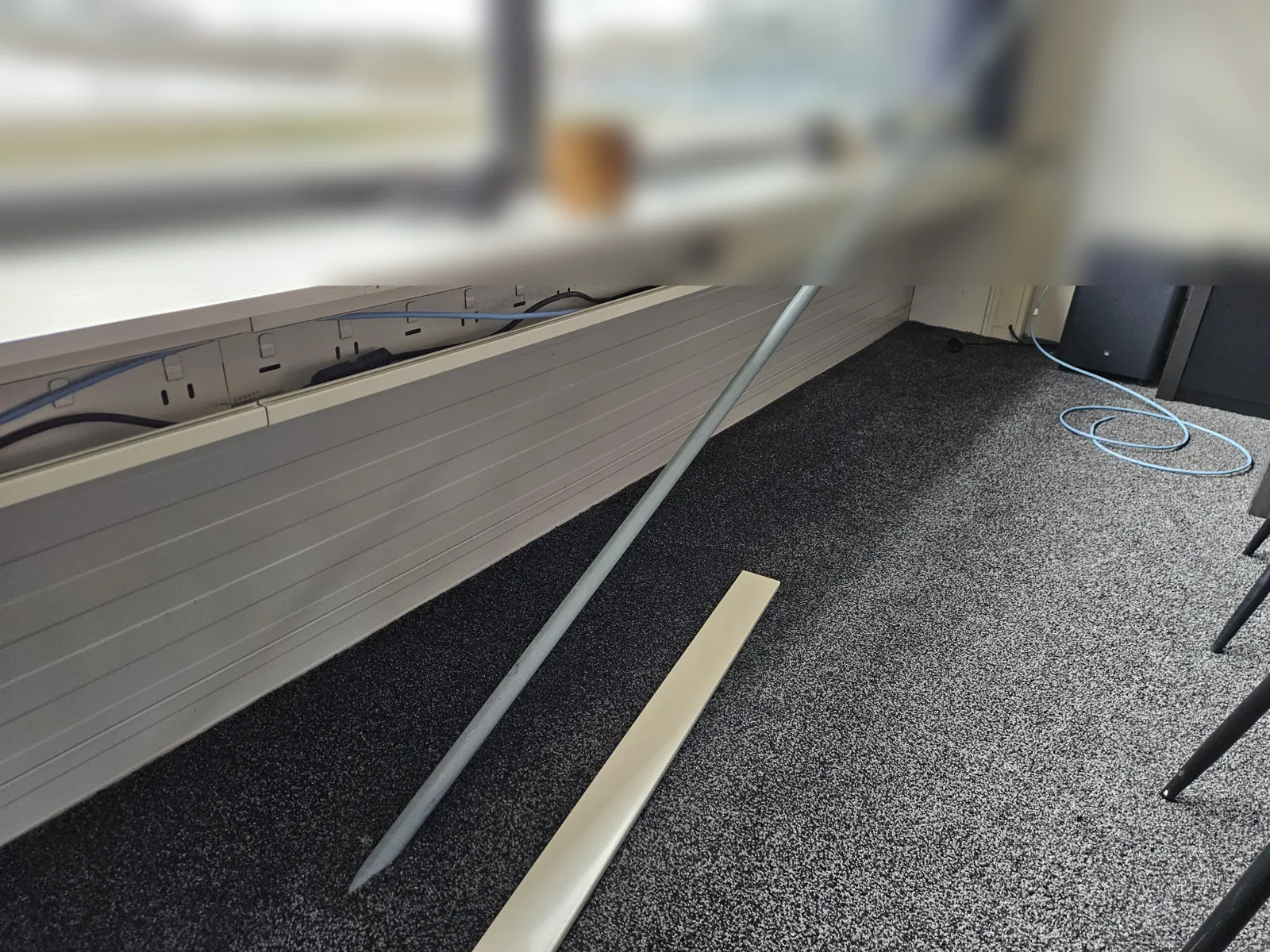Kabelgoot langs de ramen op de vide van een kantoor in Amsterdam, met een lichtblauwe kabel naar de werkplek