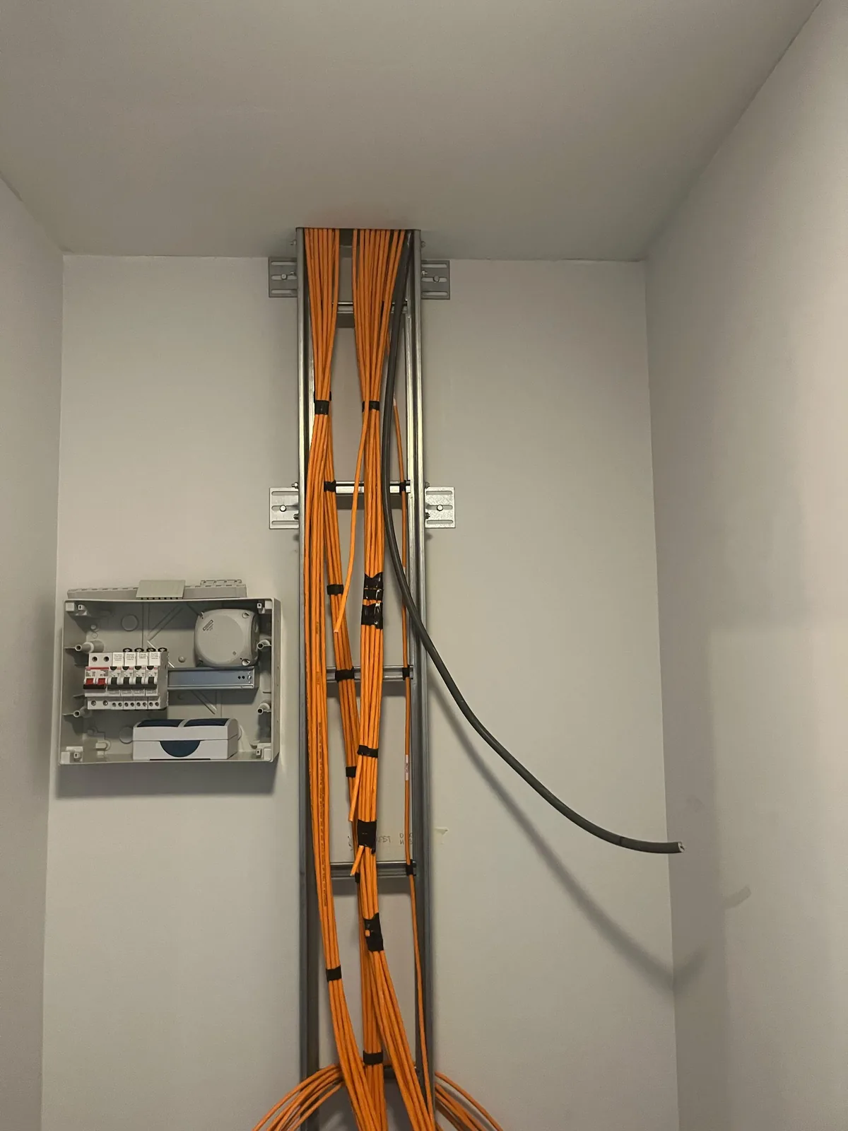 Verticale kabelladder in de technische ruimte van een kantoorpand in Utrecht, met twee bundels oranje netwerkkabels die van de verdieping naar beneden komen