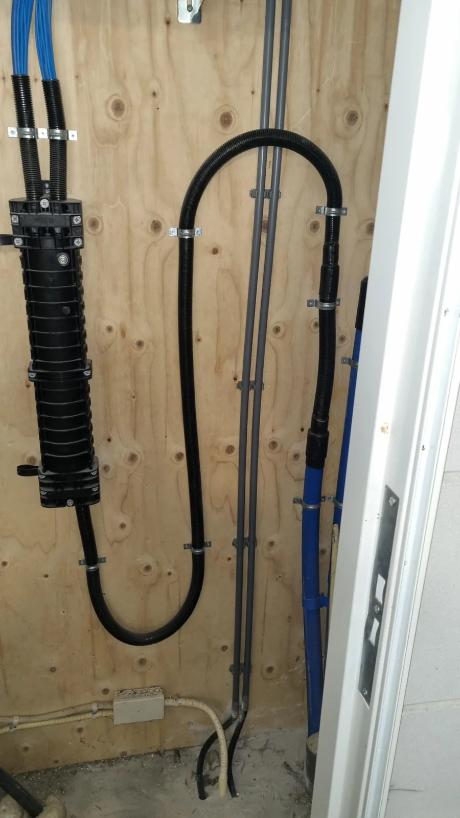 Kabels in zwarte buis strak langs de wand van de techniekruimte