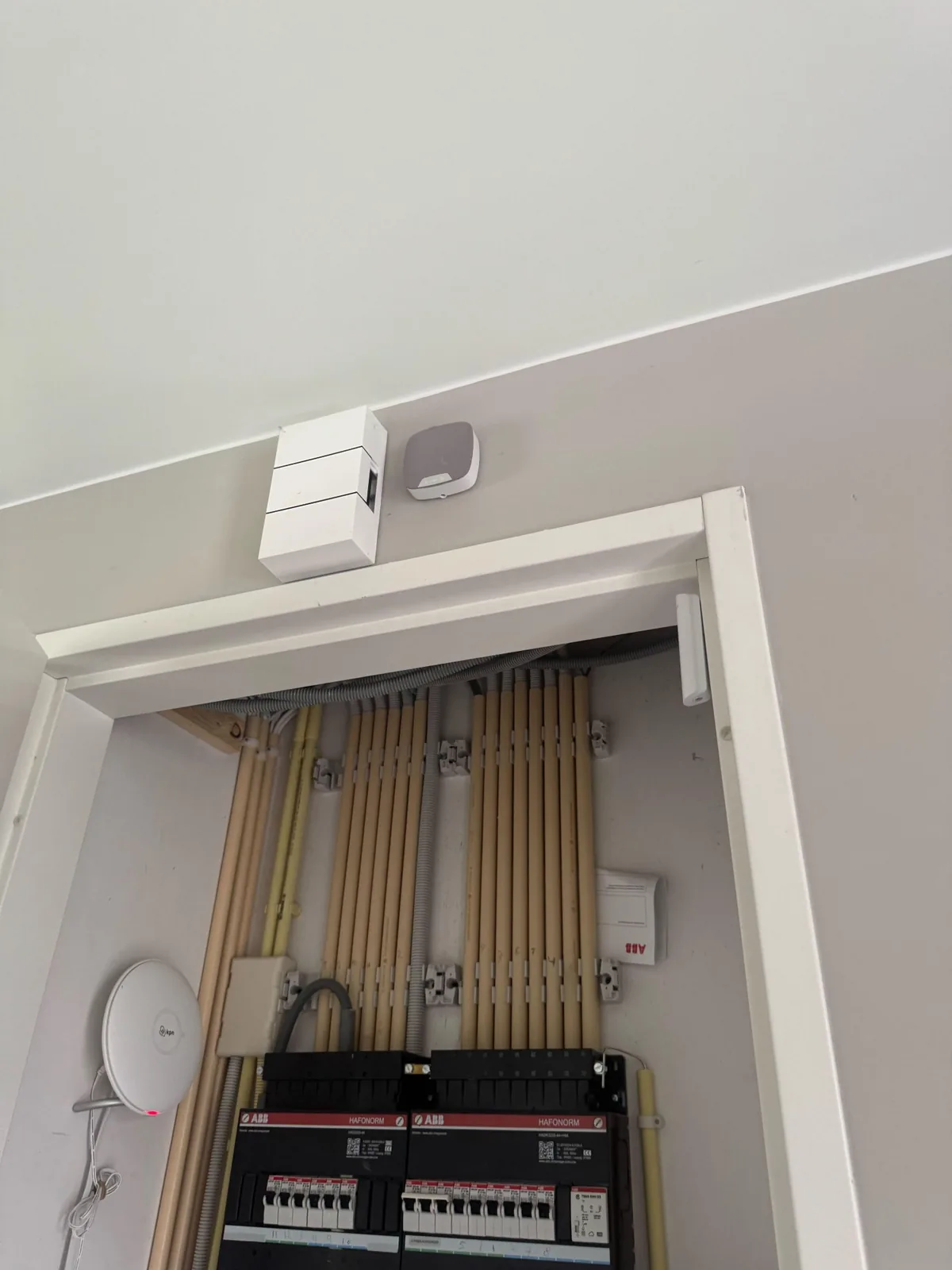 Meterkast met de Ajax-hub, en erboven een witte binnensirene en een contact, bij een woning in Blaricum