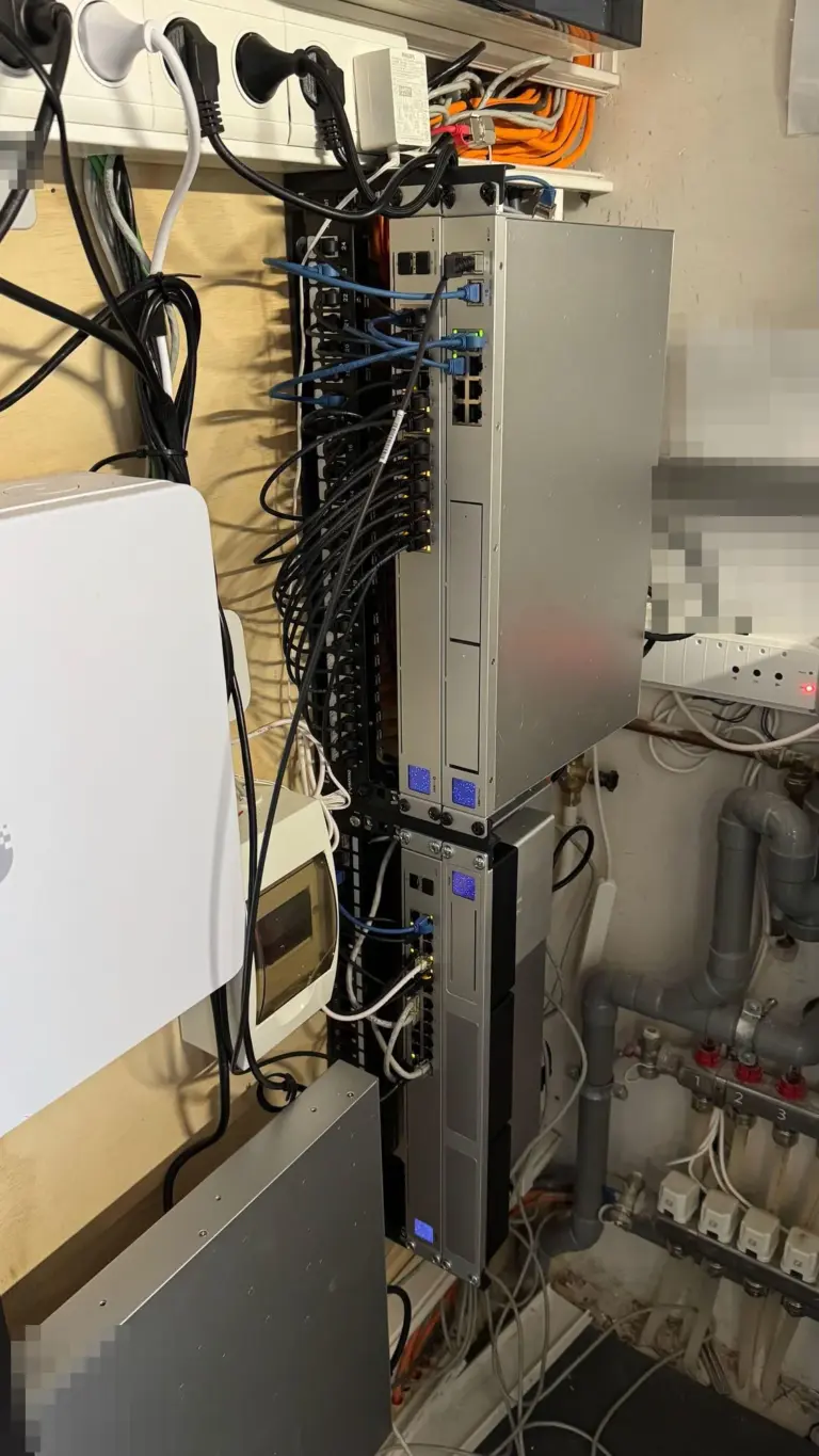 Meterkast van een bedrijf met UniFi Dream Machine Pro Max en switches naast het patchpaneel, opnieuw bekabeld met korte patchkabels
