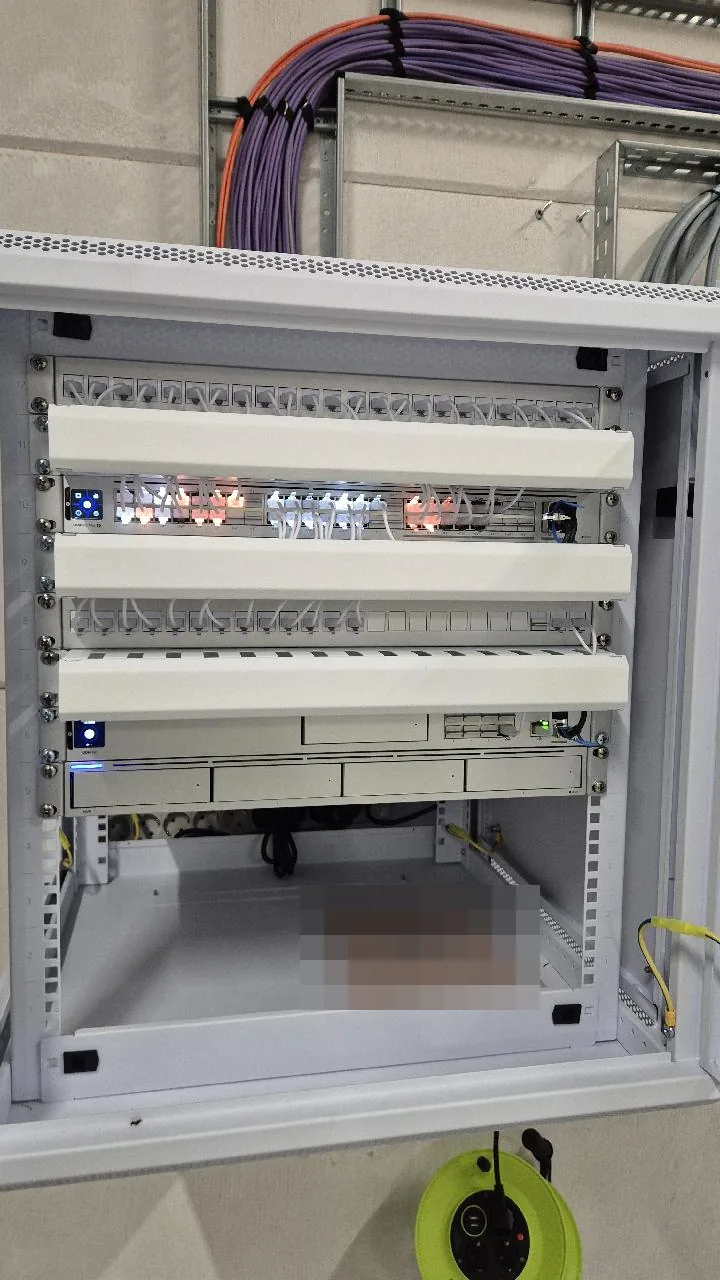 Patchkast van 12U met een UniFi Dream Machine en paarse netwerkkabels
