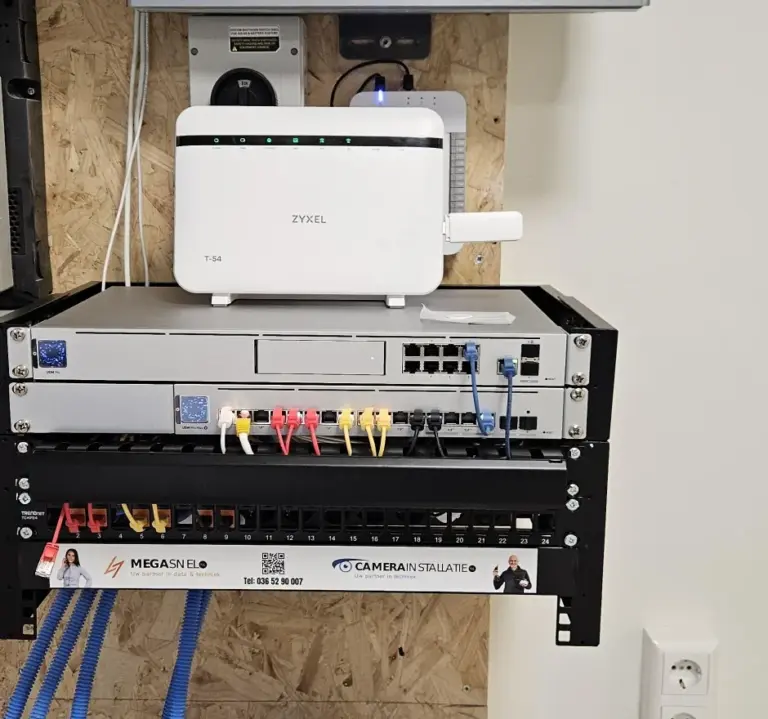 Patchrek in de kelder met een UniFi-router, een PoE-switch en een patchpaneel met gekleurde patchkabels, het modem bovenop