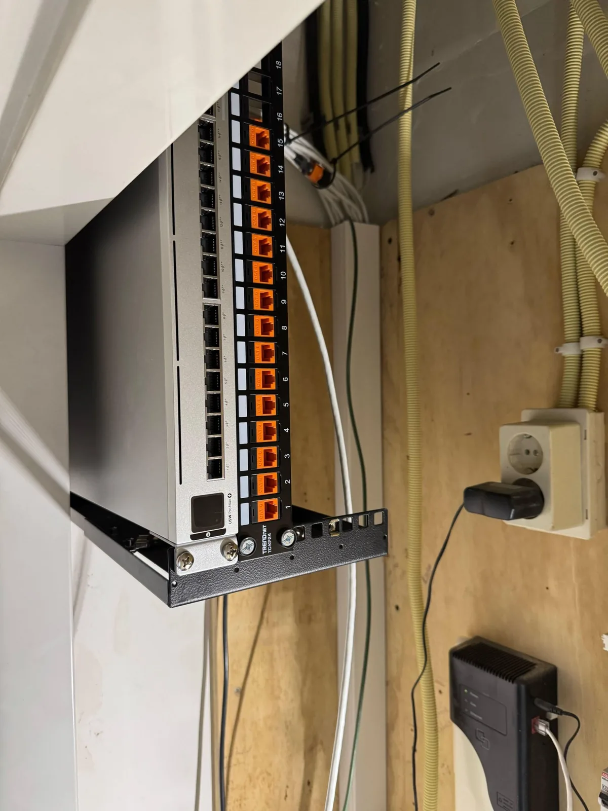 Patchrek in de meterkast met een patchpaneel vol oranje keystones en netjes geleide kabels
