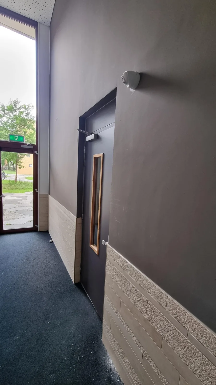 Witte Dahua Starlight-camera aan de wand bij de achterdeur van een appartementengebouw