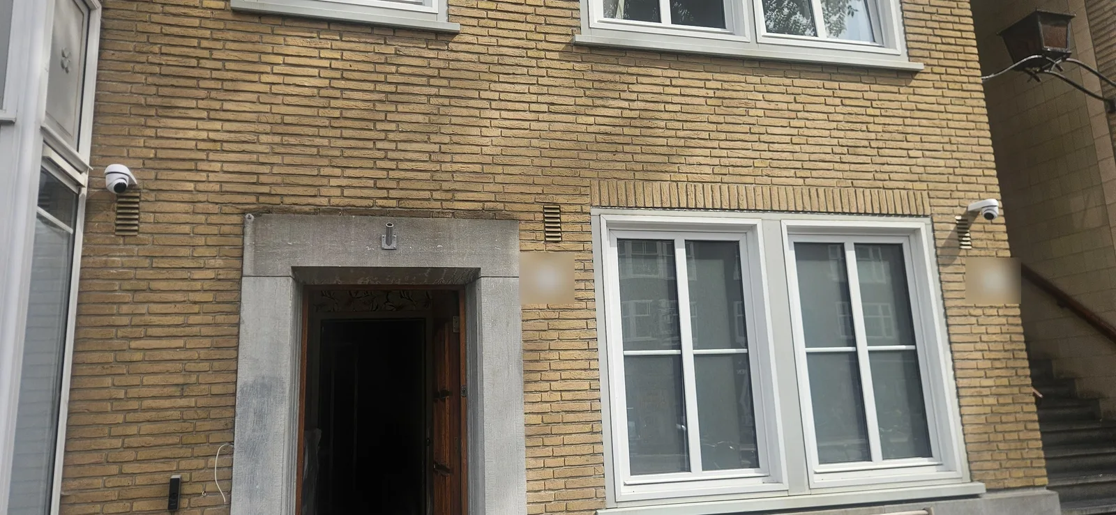 Gele bakstenen gevel met twee witte UniFi G6-camera’s links en rechts boven de ramen