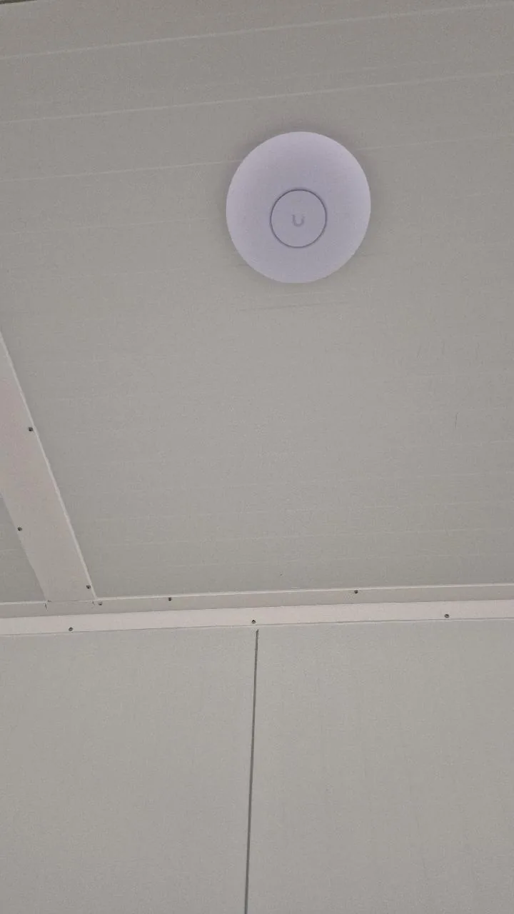 Rond UniFi-access point aan een wit plafond
