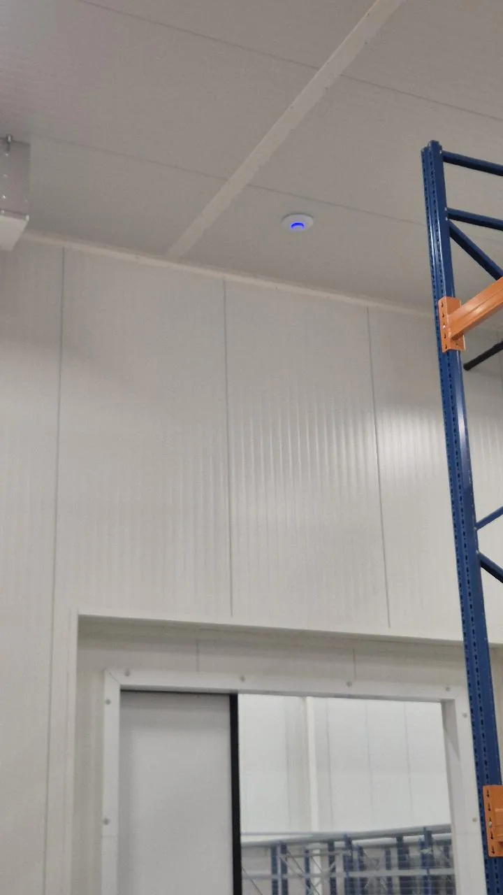 UniFi-access point aan het plafond van de koelcel in een warehouse in Almere, boven stellingen en een schuifdeur