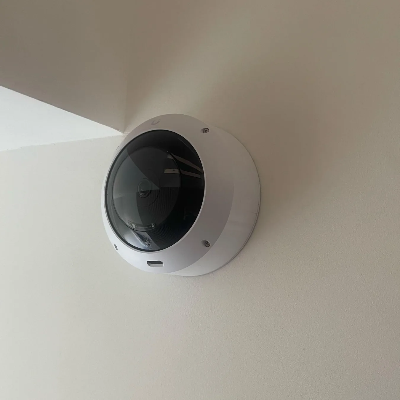 Witte UniFi-domecamera binnen in de hoek, vlak onder het plafond