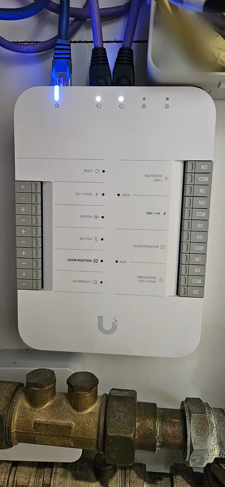 Witte UniFi Door Hub in de meterkast, met aangesloten netwerkkabels en brandende lampjes
