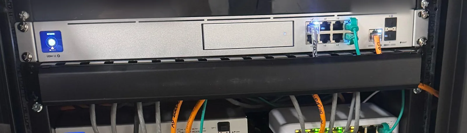 UniFi Dream Machine SE in de patchkast met aangesloten netwerkkabels en een kabelgeleider eronder