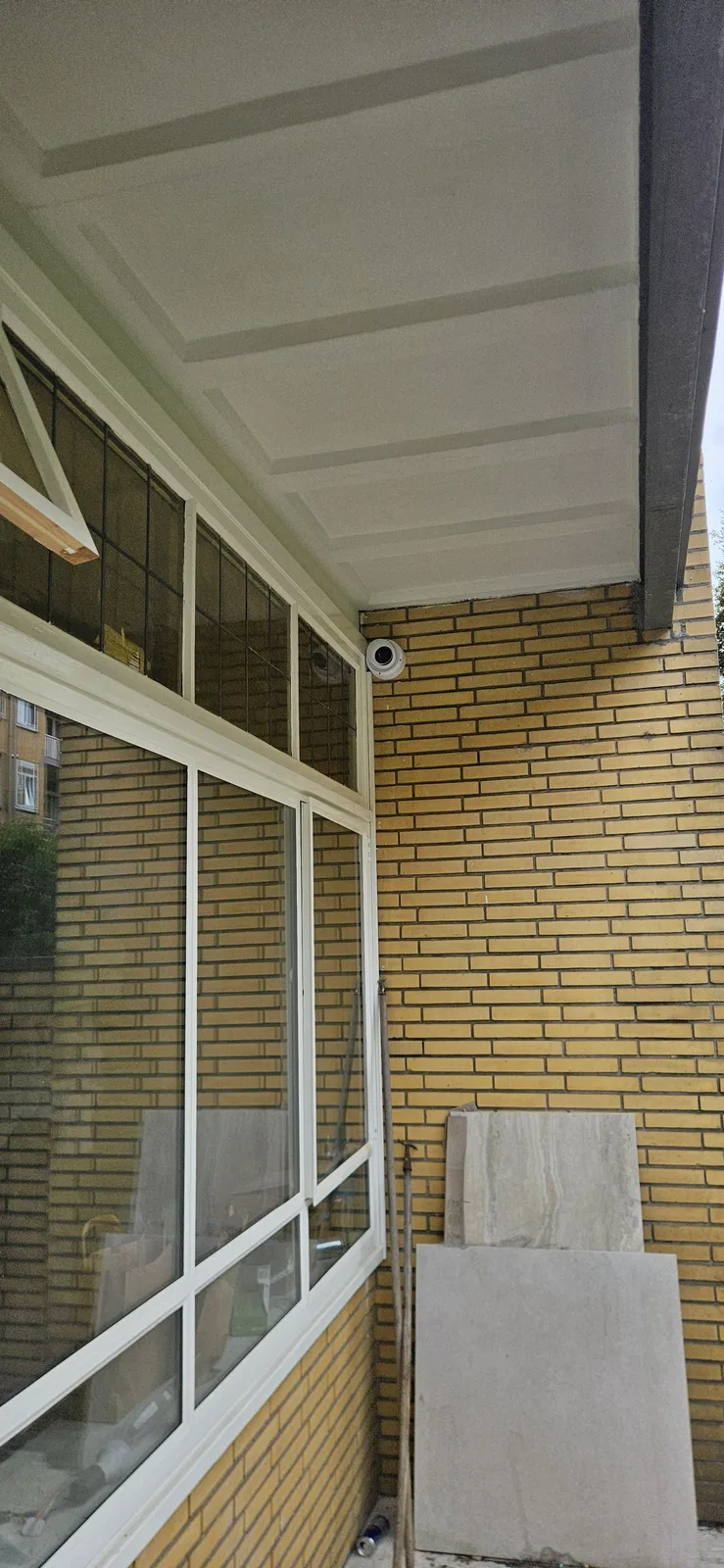 Witte UniFi G6-camera in de hoek onder de overkapping aan de achterzijde
