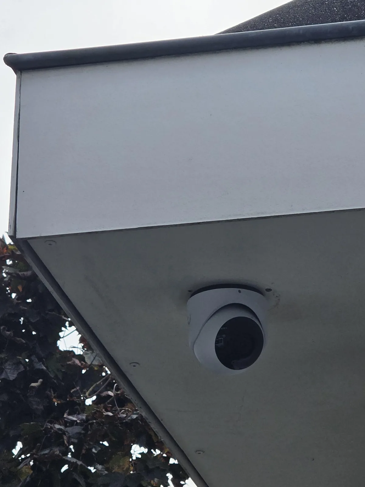 Witte UniFi G6 Turret onder de witte dakrand op de hoek van een woning in Bosch en Duin