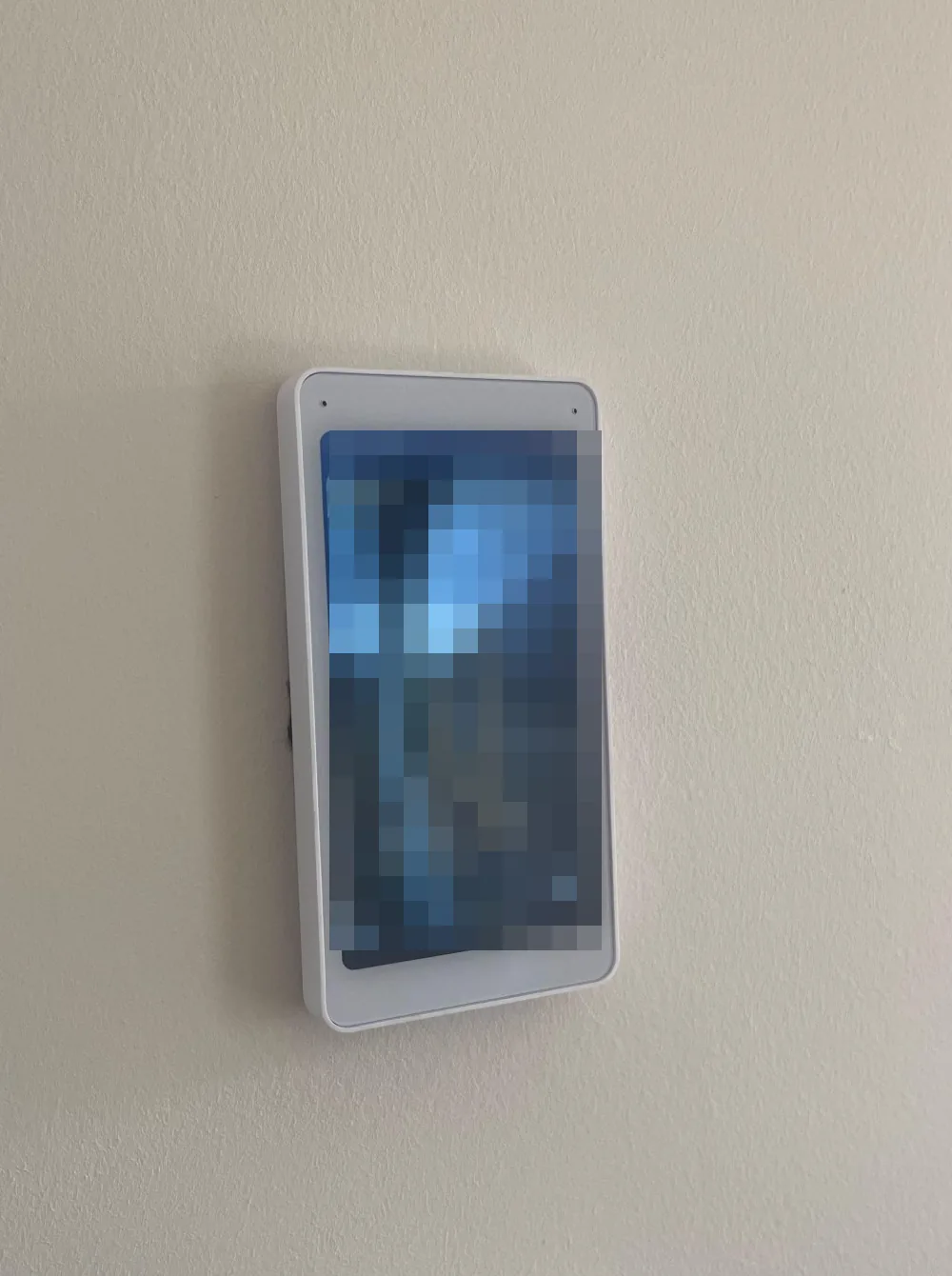Wit UniFi Intercom Viewer-scherm aan de wand in de woonkamer; het live beeld op het scherm is onherkenbaar gemaakt