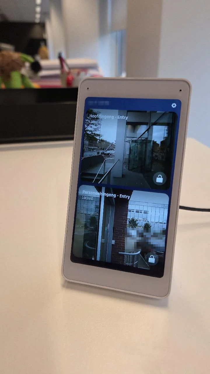 UniFi Intercom Viewer op een bureau met live beeld van de hoofdingang bij de draaideur en van de personeelsingang van een kantoor in Den Haag