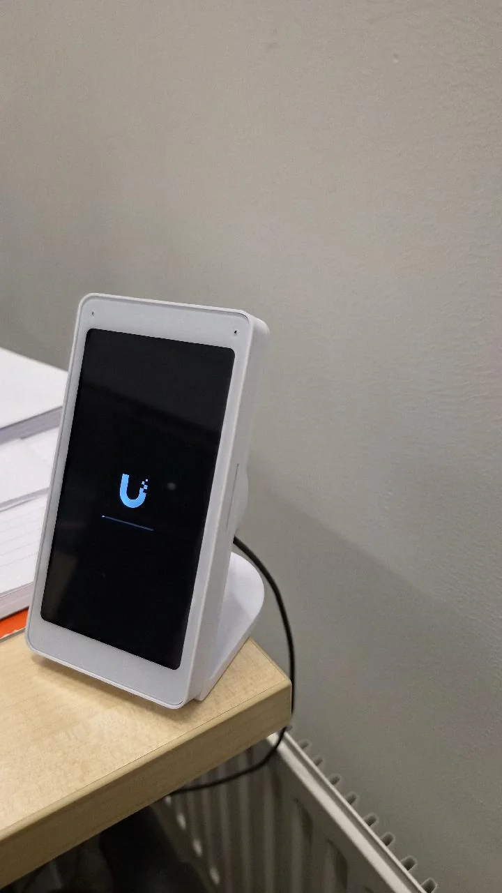 Witte UniFi Viewer op een tafelstandaard die net opstart, het UniFi-logo op het scherm