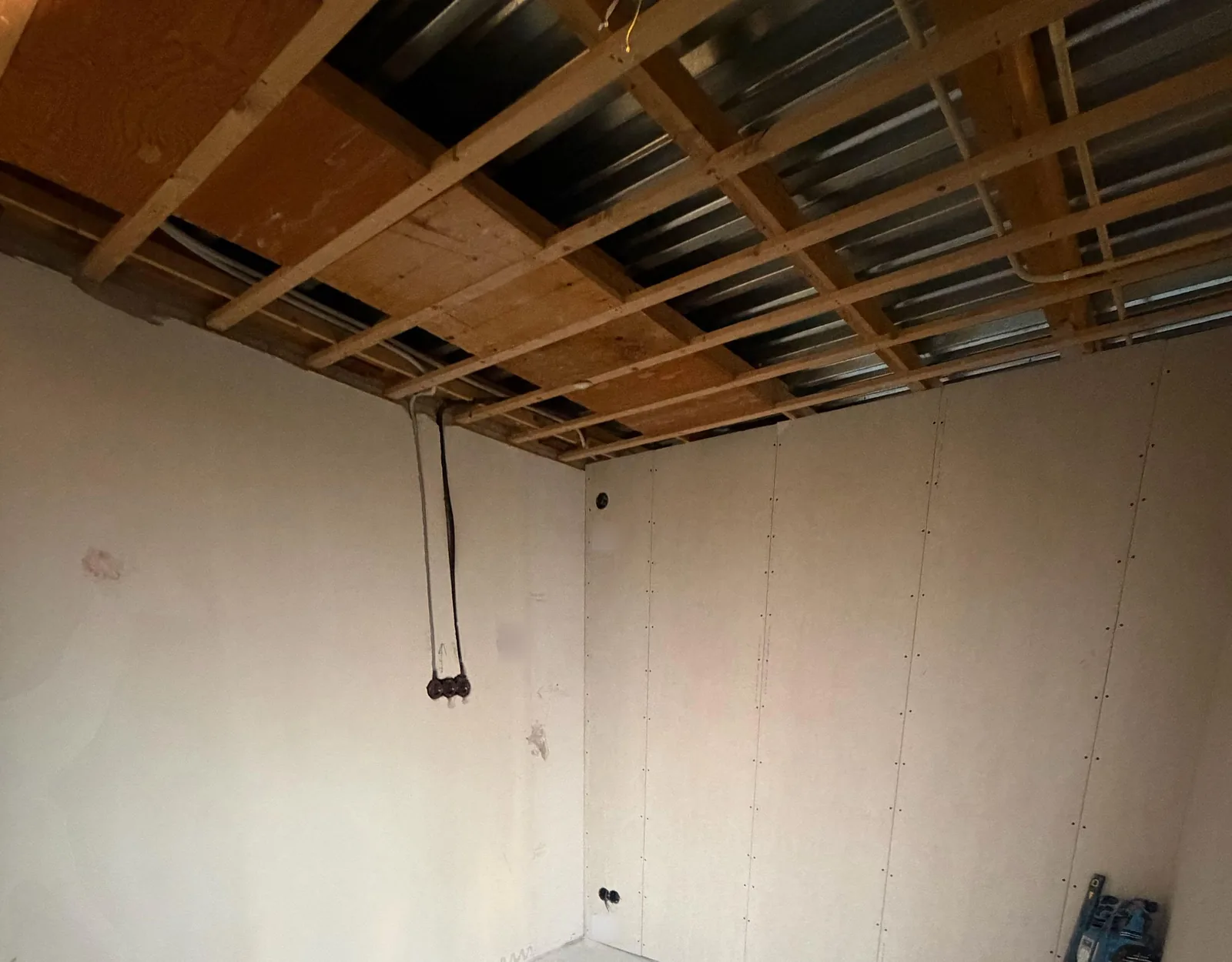 Lege kamer op de eerste verdieping met een open plafond van houten regels en staalplaat, en flexbuizen die al klaarliggen