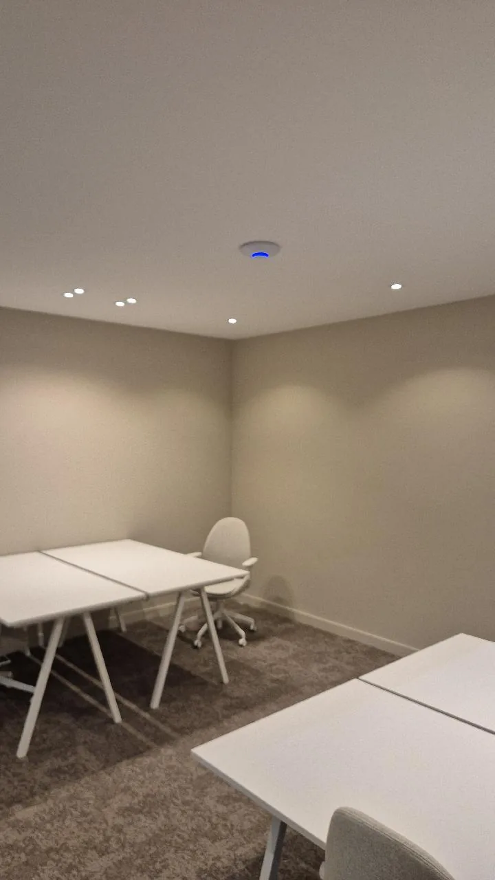 Vergaderruimte met tafels en een UniFi-access point aan het plafond