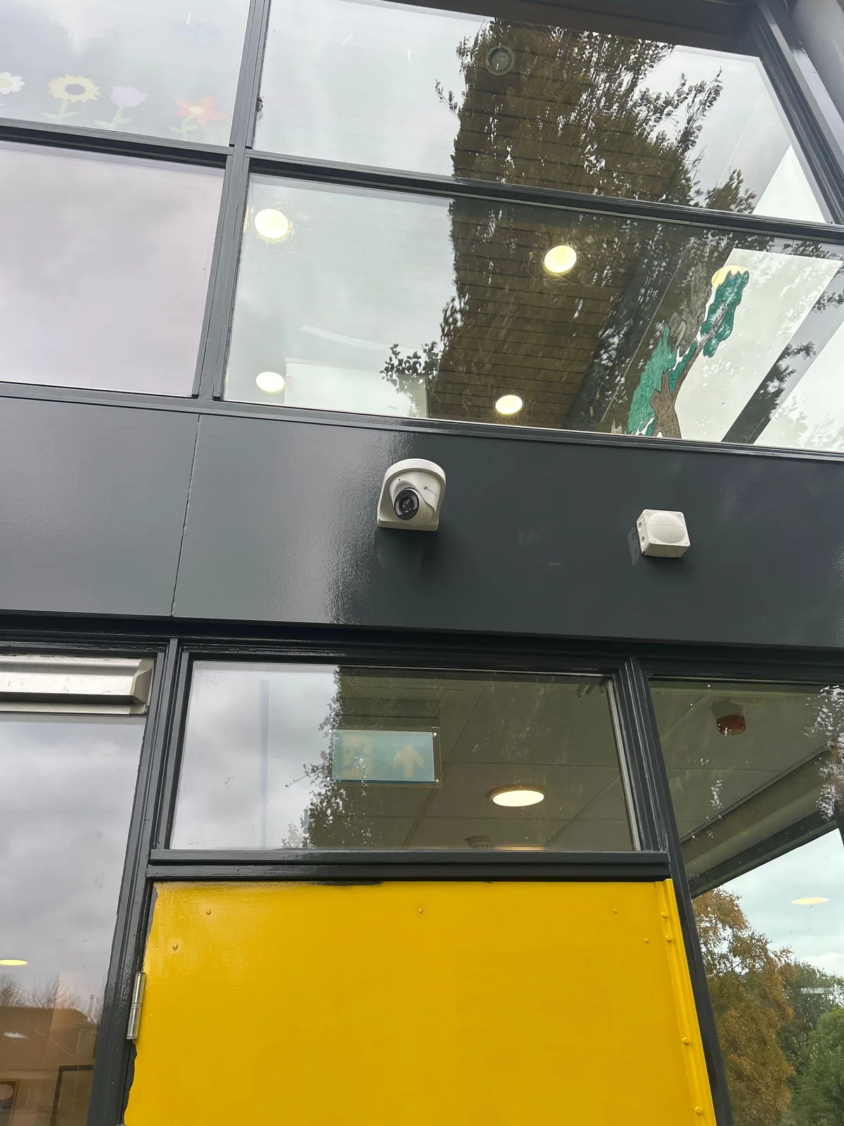 Witte VIGI-camera van 8 MP op de donkere gevelband boven de gele voordeur van een kinderdagverblijf in Almere