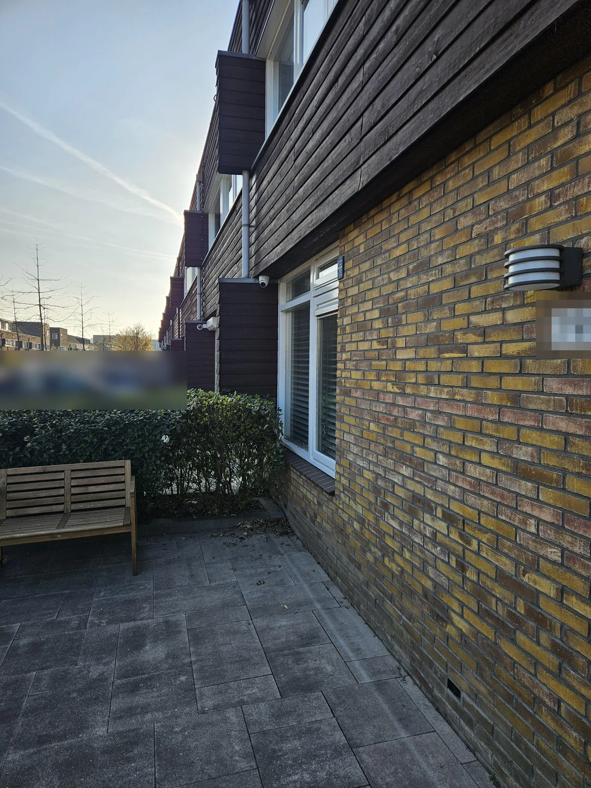 Voorgevel van een rijwoning in Almere met houten betimmering, de camera klein onder het overstek