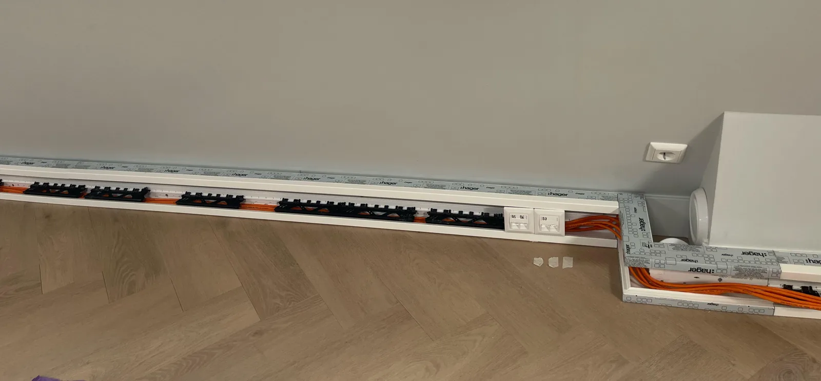 Open wandgoot langs de muur van een kantoor in Utrecht, met oranje netwerkkabels in de houders en twee aansluitpunten in de goot
