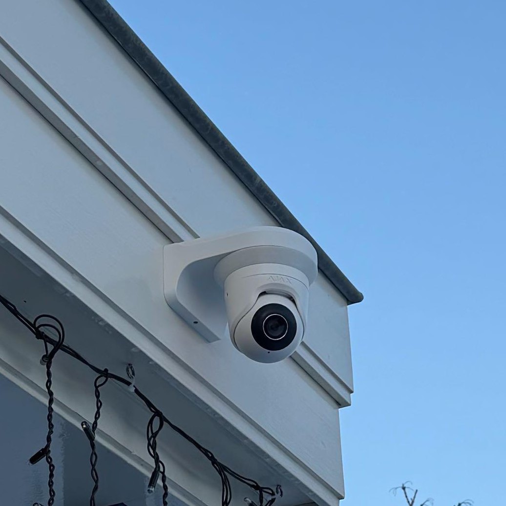 Witte camera op een witte beugel onder de dakrand, van dichtbij