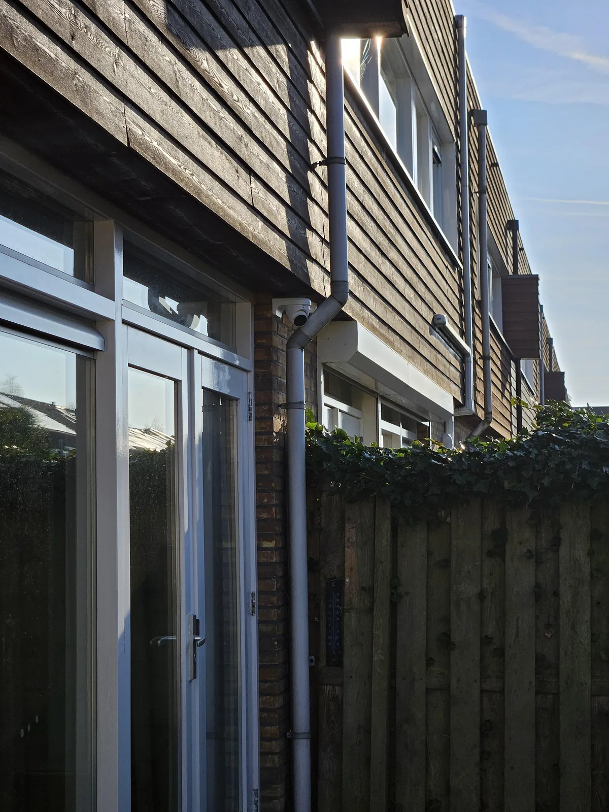 Witte Dahua-camera onder de dakrand aan de achterkant van een woning in Almere, naast de regenpijp