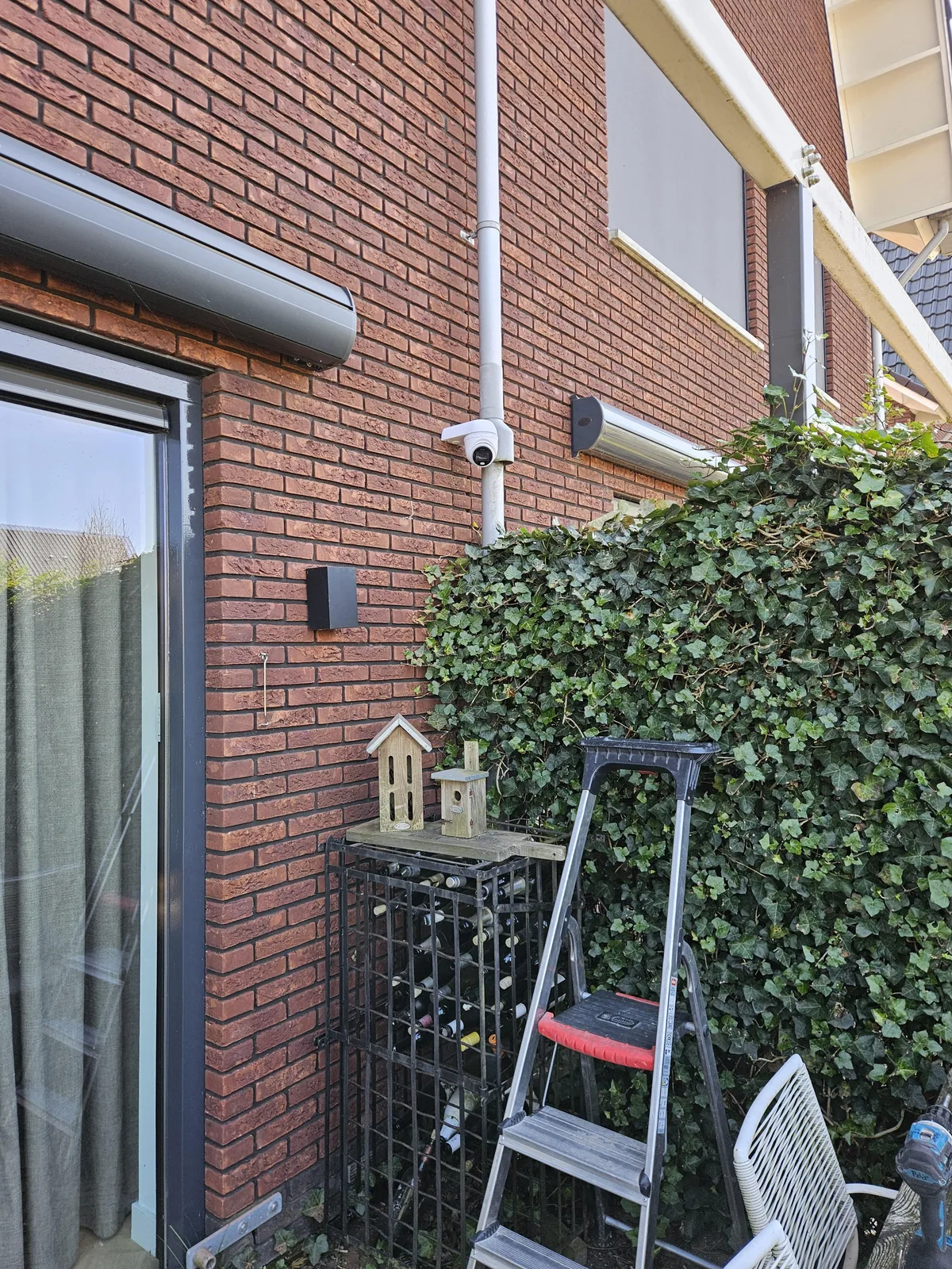 Achtergevel van een woning in Amstelveen met hoog naast de tuindeur een witte UniFi AI Turret