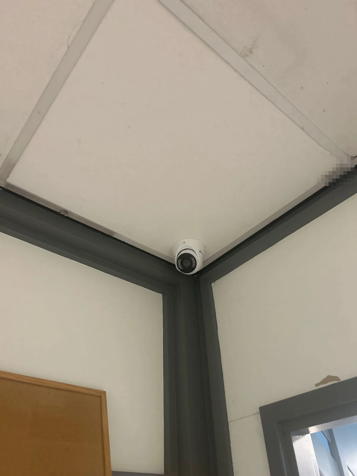 Witte VIGI-turret in de hoek van een systeemplafond, boven grijze kozijnen in een kinderdagverblijf in Almere