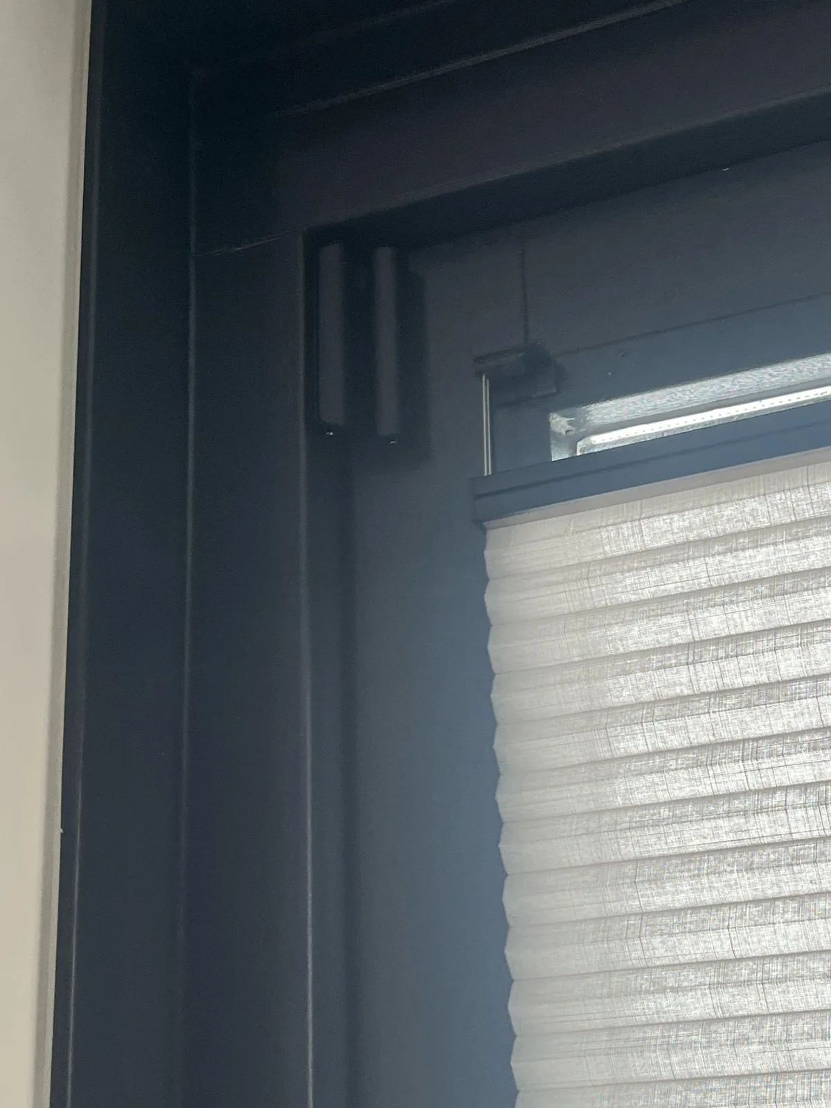 Zwart Ajax DoorProtect-contact boven in een zwart raamkozijn