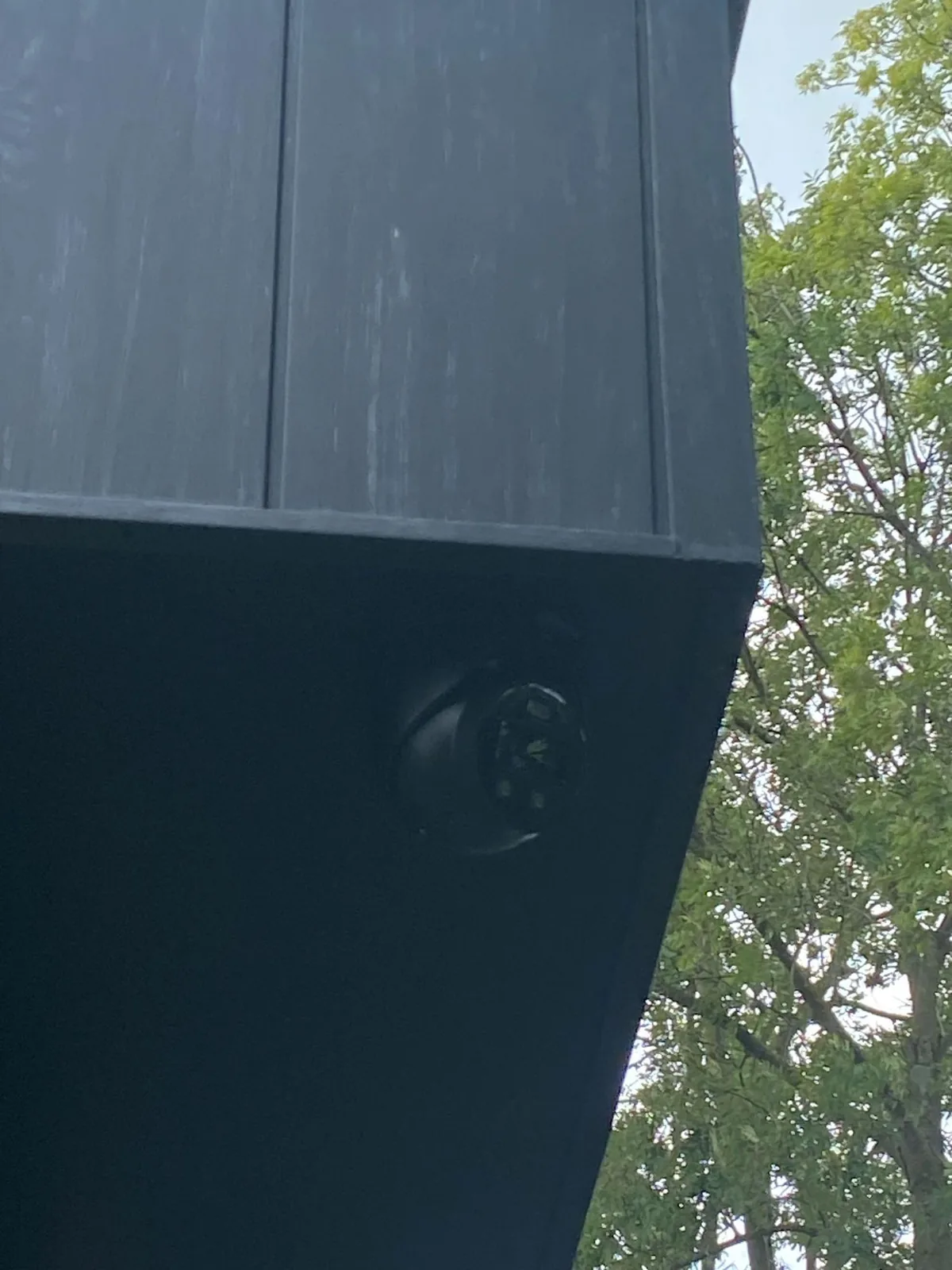 Zwarte camera onder het donkere overstek, met een boom ernaast