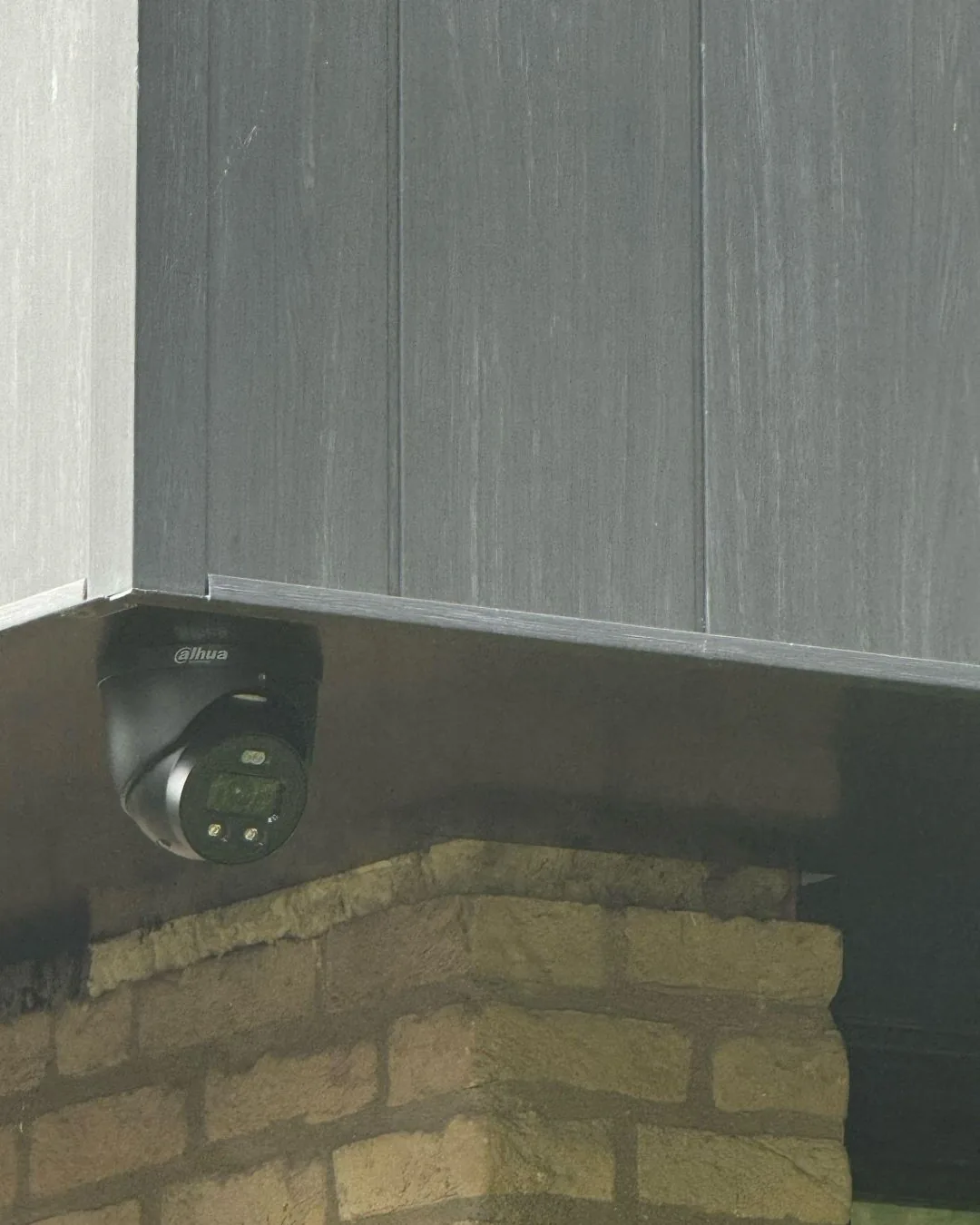 Zwarte Dahua-camera onder het overstek, boven de gele baksteen, bij een woning in Hilversum met Ajax-alarm